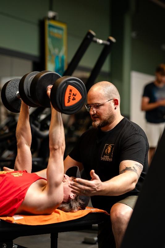 Lionel begeleidt een klant bij dumbbell press